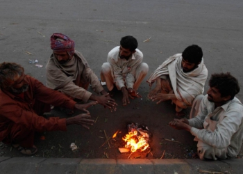 Fruit sellers sit around a fire to keep themselves warm during early morning hours along a road in Karachi December 30, 2013. Cold and dry weather is expected in most parts of the Sindh province during next 24 hours, according to Pakistan Meteorological Department website. REUTERS/Akhtar Soomro (PAKISTAN - Tags: ENVIRONMENT)