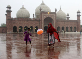 Pakistani children play in the rain outside the historical Badshahi mosque in Lahore, Pakistan, Friday, July 24, 2015.  Pakistani authorities say flash floods, triggered by monsoon rains, have killed 12 more people across the country, bringing the overall death toll since early last week to 15, as rescuers struggle to move those stranded to safer places. (AP Photo/K.M. Chaudary)