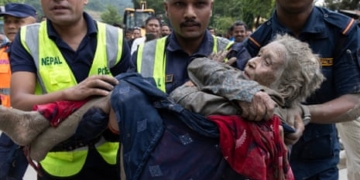 نیپال کے تریشولی بازار میں سیلاب کے بعد امدادی اہلکار ایک خاتون کو محفوظ مقام پر منتقل کررہے ہیں
